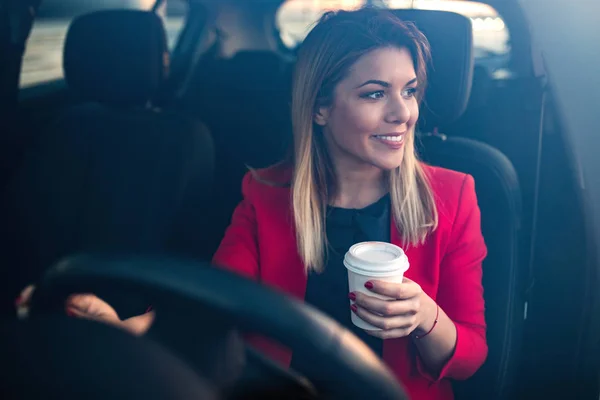 Woman sipping a coffee while driving a car.