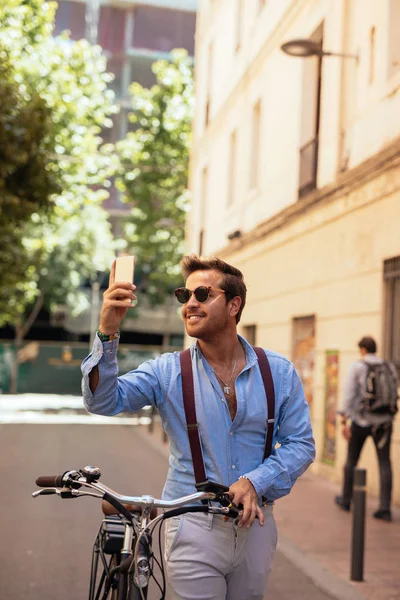 Hombre Guapo Haciendo Una Selfie Mientras Empuja Una Bicicleta Ciudad — Foto de Stock