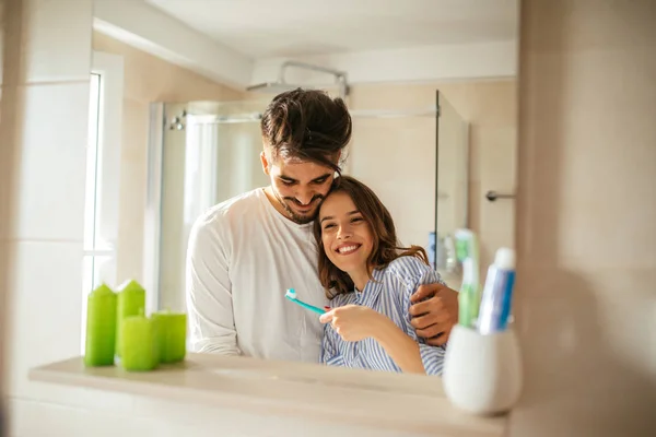 微笑着对年轻的夫妇相拥在早上例程在浴室里的肖像 — 图库照片