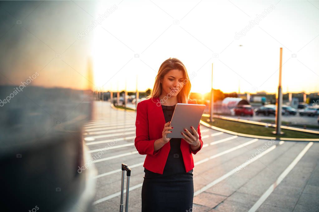 Shot of a lovely business woman using digital tablet at the airport at sunset.