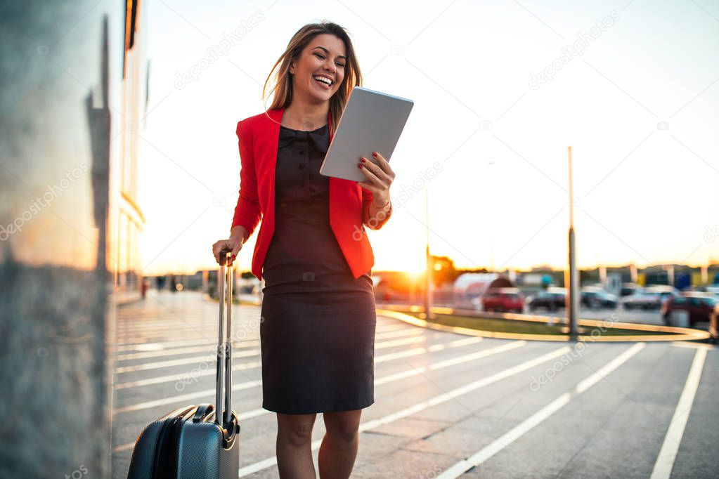 Shot of a beautiful smiling business woman using digital tablet at the airport.