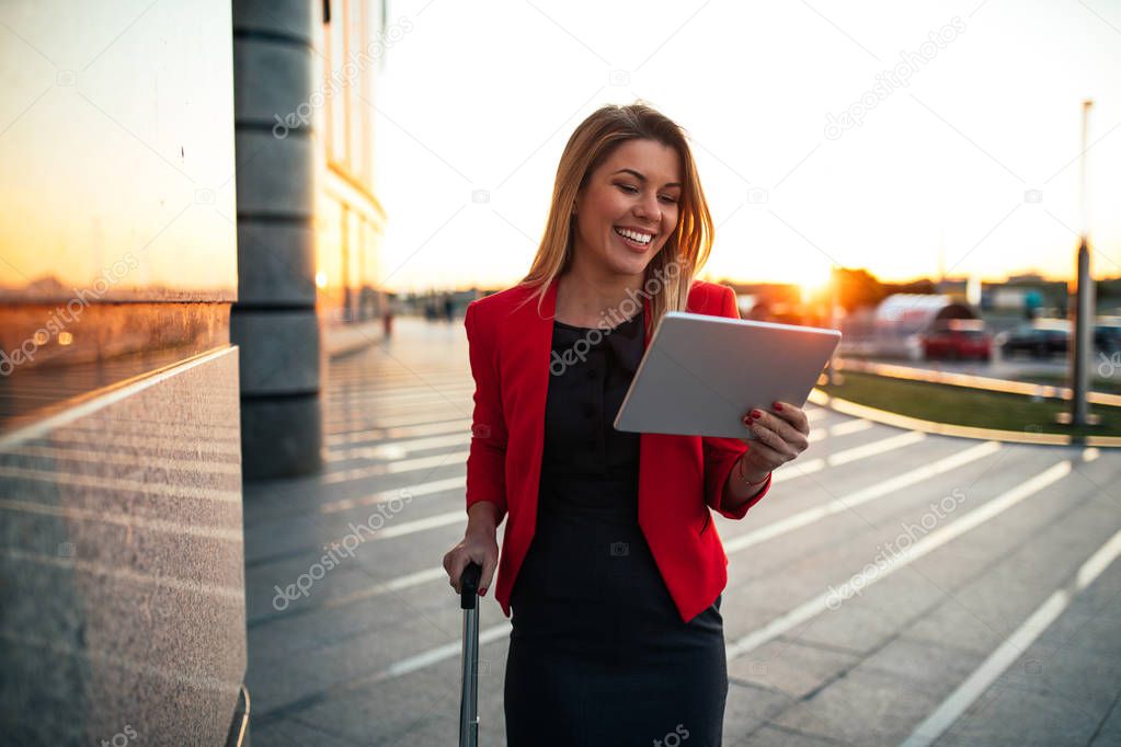 Shot of a smiling woman using digital tablet at the airport.