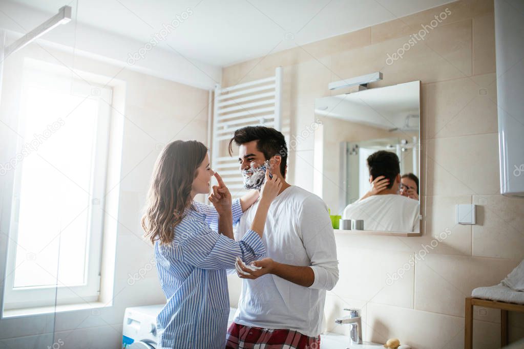 Portrait of young happy couple getting ready together in the bathroom.