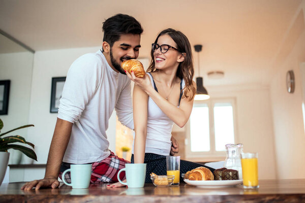 Photo of a happy young couple enjoying spending time together while having breakfast in the kitchen.