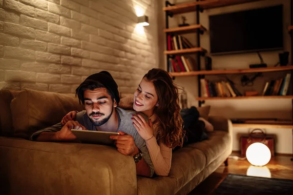 Photo Young Couple Lying Sofa Having Fun Digital Tablet — Stock Photo, Image