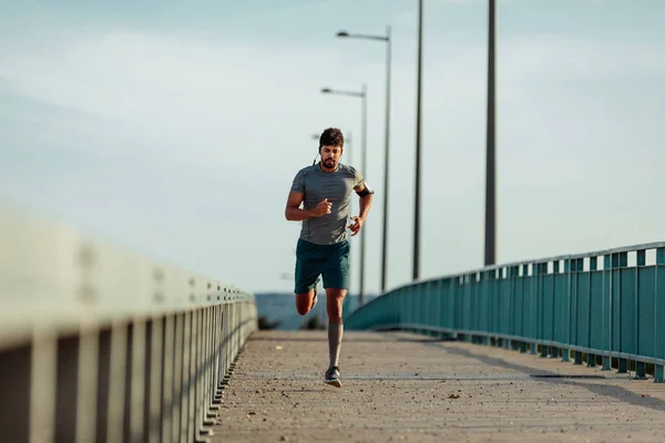 Άνδρας Αθλητής Τρέχει Στη Γέφυρα Και Ακούτε Μουσική — Φωτογραφία Αρχείου