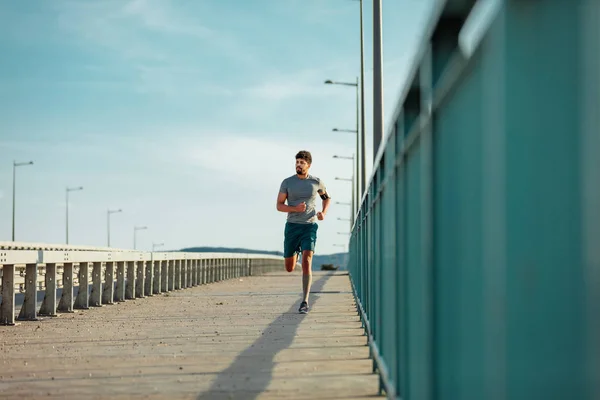 Αθλητής Άνθρωπος Απολαμβάνει Τρέχει Στη Γέφυρα Και Ακούτε Μουσική — Φωτογραφία Αρχείου