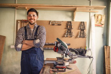 Gülümseyen genç marangoz atölyesinde çalışan portresi.