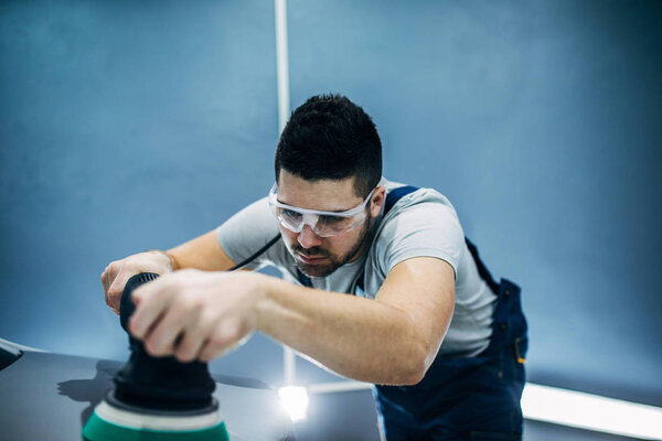 Снимок автомеханика, полирующего автомобиль
.