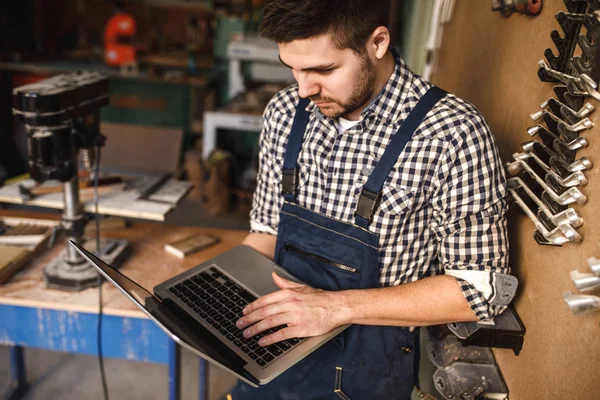 Genç bir marangoz atölyesini sonra işte dizüstü kullanarak portresi.