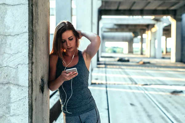 Woman using mobile phone for setting running play list.