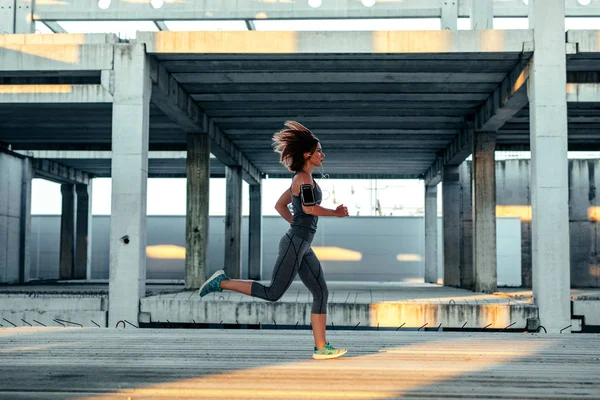 Tam uzunlukta çalıştıran ve terk edilmiş eski bir binada müzik dinlemek bir sporcu kadın portresi.