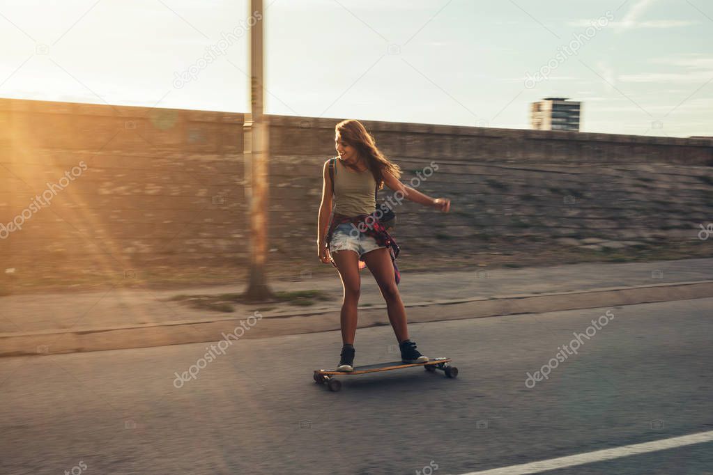 Happy teenager driving a longboard in the city.