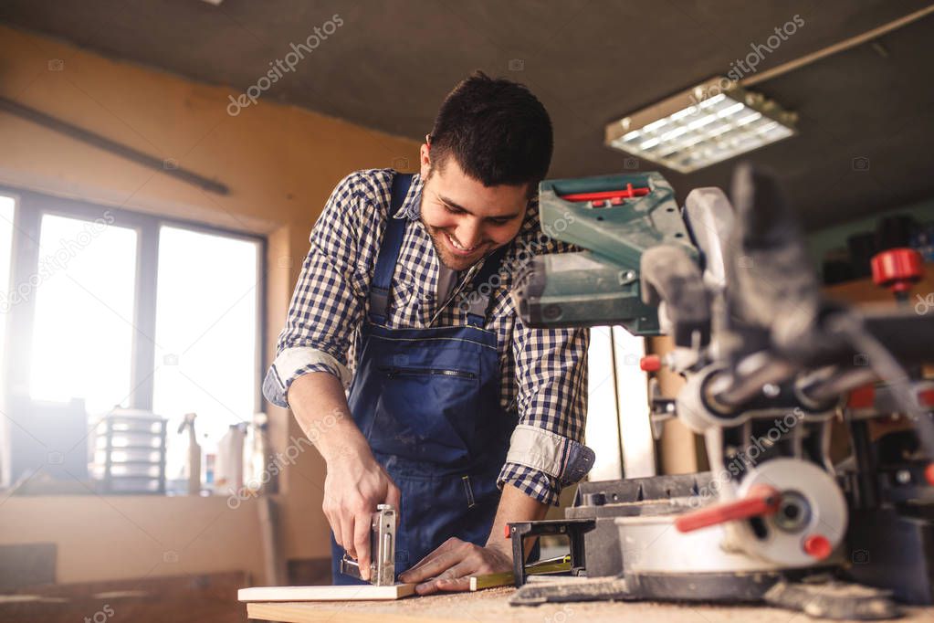 Photo of satisfied young carpenter enjoying in his work.