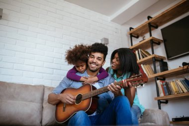 Birlikte şarkı ve gitar evde oynarken zevk bir Afro-Amerikan aile portresi.