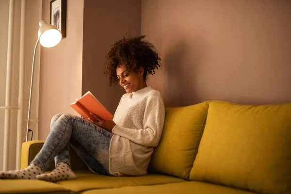 Portret Piękne African American Kobieta Uśmiechający Się Czytając Książkę Domu — Zdjęcie stockowe