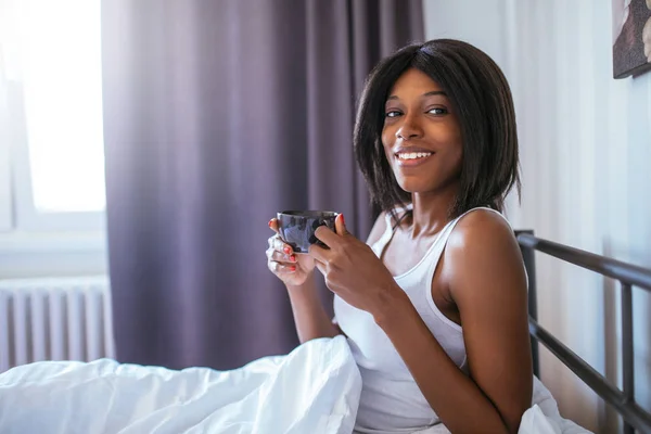 침대에서 커피를 마시는 아프리카계 미국인 여자의 초상화 — 스톡 사진
