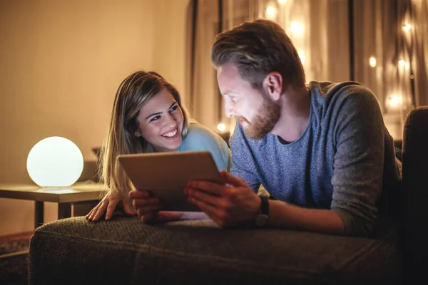 Photo of young couple watching a movie on a digital tablet at home.