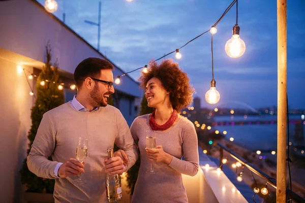 Happy couple enjoying drinks and balcony party.