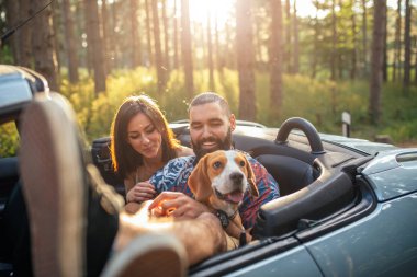Modern genç bir çift ile bir köpek açık havada arabada ürpertici zevk portresi.