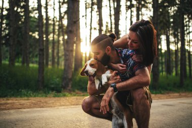 Mutlu bir çift açık havada doğada bir köpekle kucaklayan portresi.