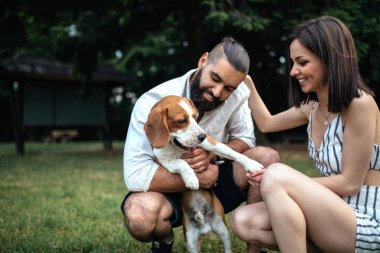 Eğleniyor gülümseyen genç birkaç kadeh bir köpekle açık havada oynamayı.