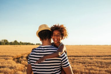 Bir Afrikalı-Amerikalı babası kızını buğday alanları taşıyan portresi.