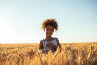 Sevimli genç Afro-Amerikan kız buğday alanında ayakta.