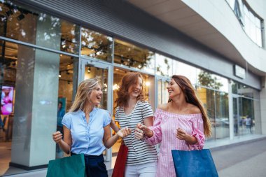 Atış üç genç kadınların açık havada alışveriş yaparken eğleniyor.