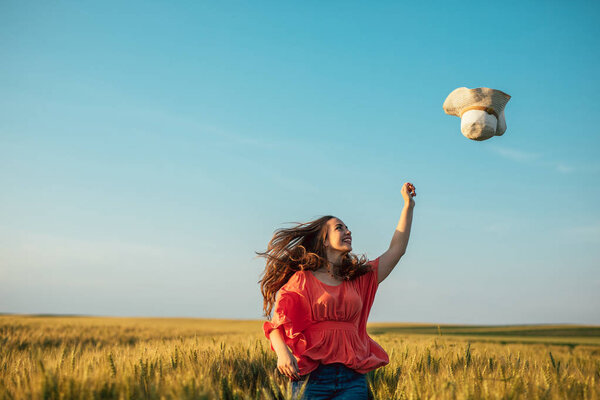 Portrait of a young woman throwing a hat in the countryside.