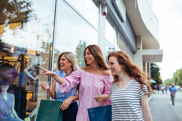 A beautiful friends carrying shopping bags while leaving the store.