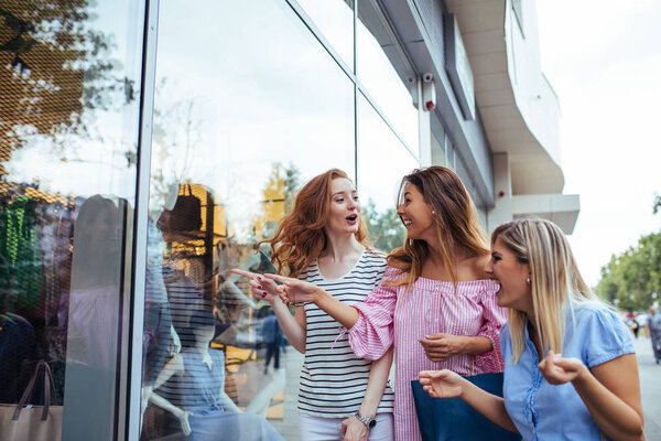 A beautiful friends carrying shopping bags while leaving the store.
