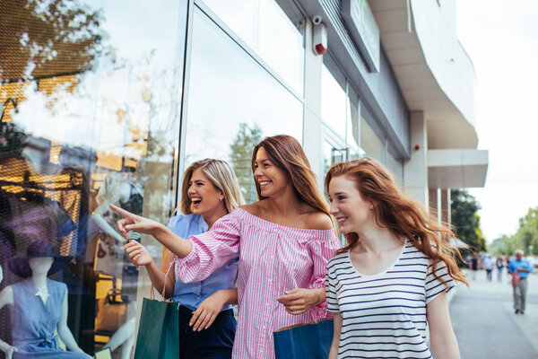Shot of three women window shopping in the city.