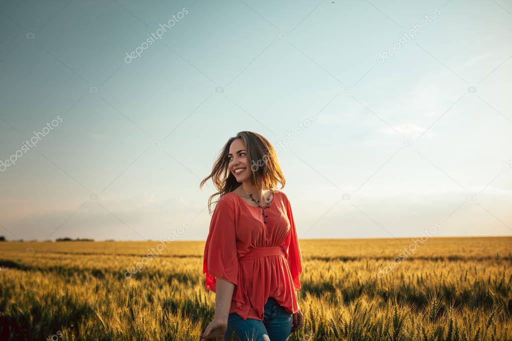 Portrait of a smiling young woman walking in the field.