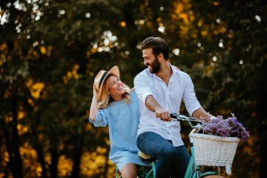 Güzel bir genç çift çiçek sepeti taşırken Bisiklete binmek eğleniyor portresi.