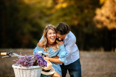 Mutlu genç çiftin bisikletle otururken bir kucaklama paylaşımı.