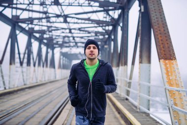 Köprüde çalışan ve müzik bir genç sporcu adam portresi.