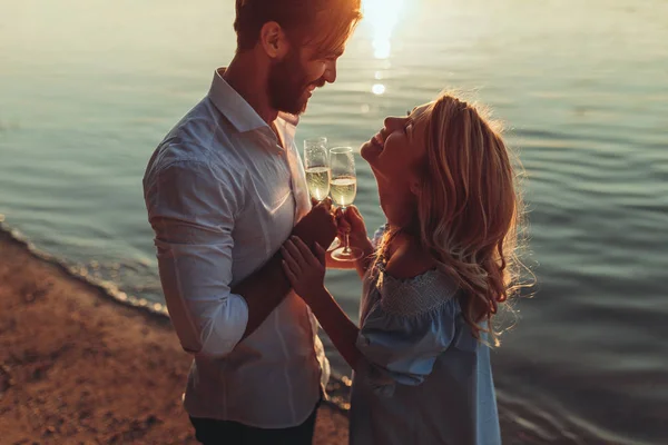 年轻夫妇的肖像在日落时与葡萄酒敬酒 — 图库照片