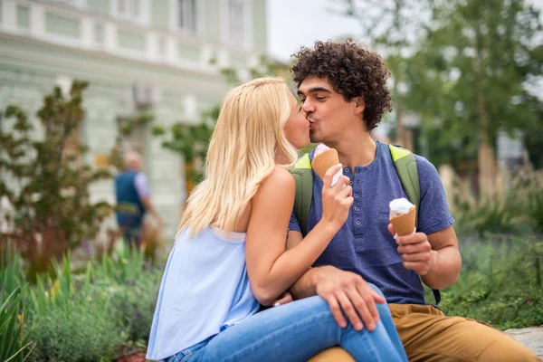アイスクリームを食べると屋外キス若いカップルの肖像画 — ストック写真