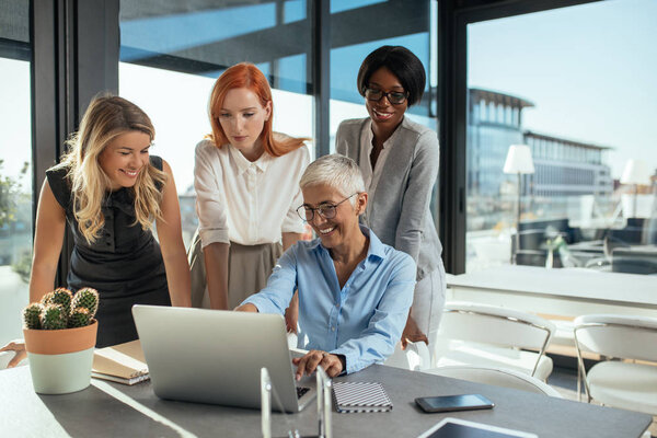 Team of businesswomen working on a laptop in a cafe.