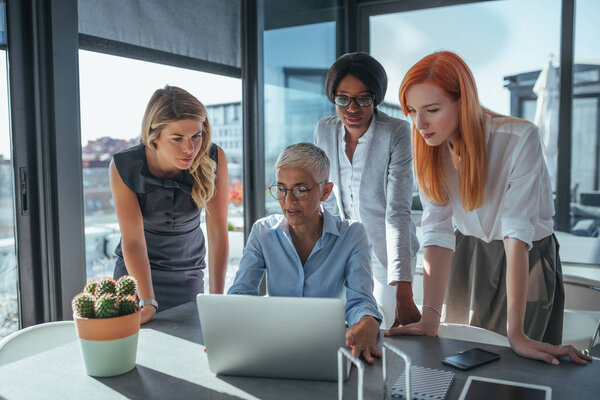 Team of businesswomen working on a laptop in a cafe.