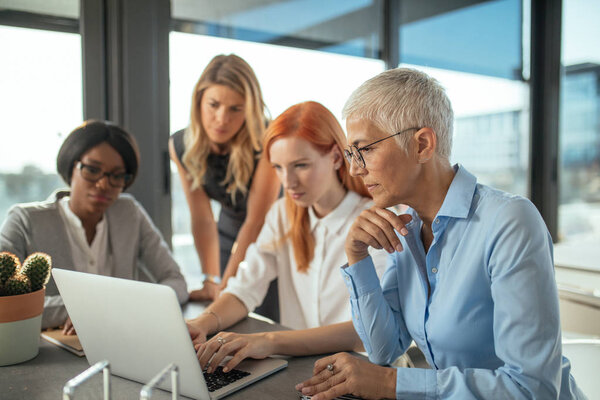 Group of female businesswomen working together on a laptop.
