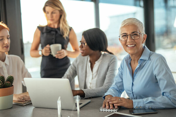 Group of female businesswomen working together on a laptop.