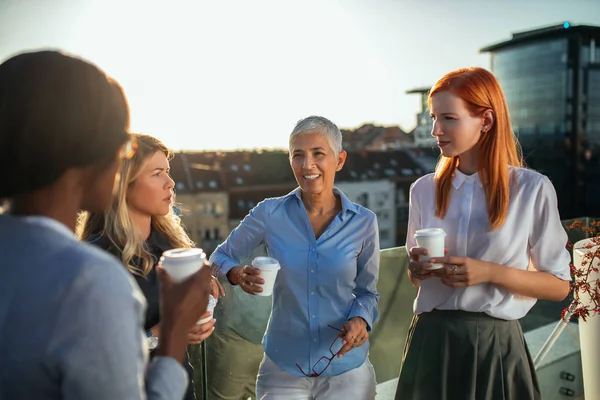 Group of businesswoman chatting while having coffee break.