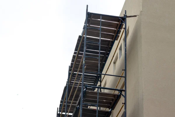 İskelelerle çevrili beyaz bir tuğla bina kahverengi yalıtım malzemeleriyle izole edilmiştir..