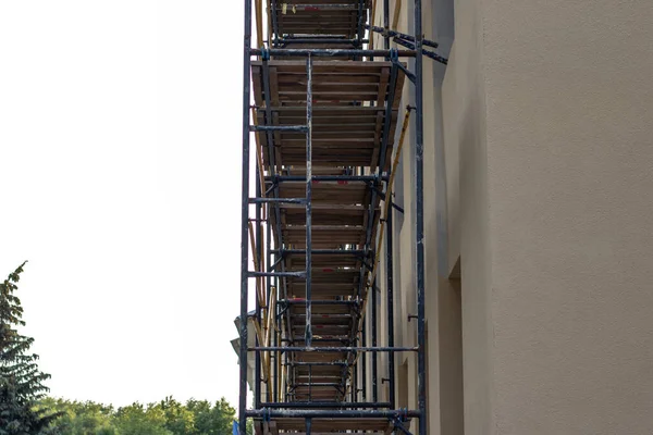 İskelelerle çevrili beyaz bir tuğla bina kahverengi yalıtım malzemeleriyle izole edilmiştir..