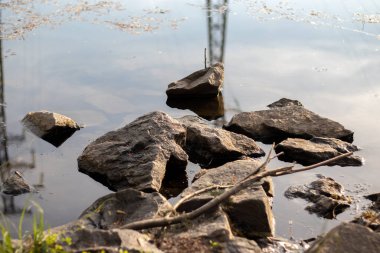 Nehir kıyısındaki suda yatan bir yığın taş ve suda yansıma. Yakın plan..
