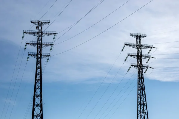 Mavi gökyüzünün arka planında bulutlu iki elektrik hattı var..