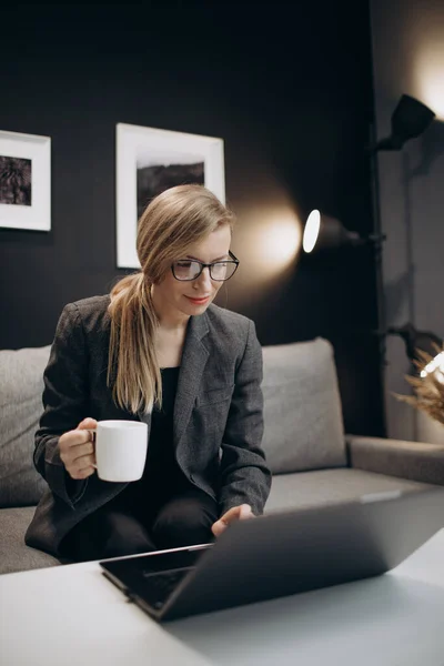 İş kadını ofiste dizüstü bilgisayar ve kahveyle oturuyor. — Stok fotoğraf