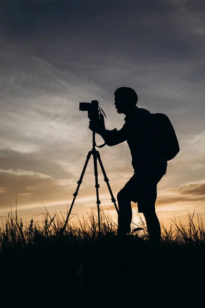 Fotógrafo en silueta usando trípode para disparar puesta de sol — Foto de Stock